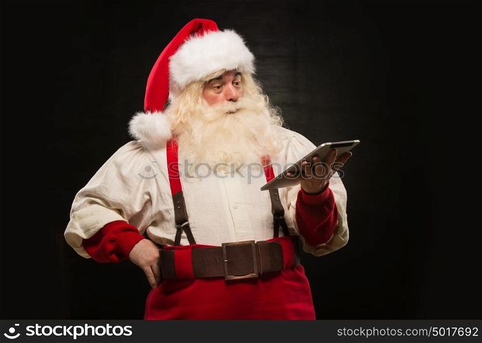 Santa Claus using tablet computer to surf internet and communicate in social media with children