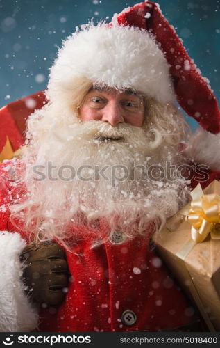 Santa Claus walking on the snow with his sack of lots of presents. Winter night with snowfall