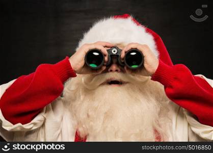 Santa Claus with binoculars against dark background