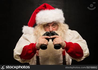 Santa Claus with binoculars against dark background