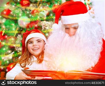 Santa Claus with little granddaughter opening magic book and saw glowing lights, spending Christmas eve near beautiful decorated tree