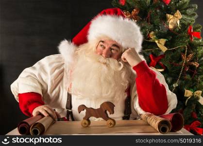 Santa Claus working - preparing and wrapping christmas gifts, toys before sending it to children