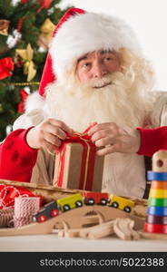 Santa Claus working - preparing and wrapping christmas gifts, toys before sending it to children