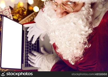 Santa Claus working with modern laptop on his lap, view from above