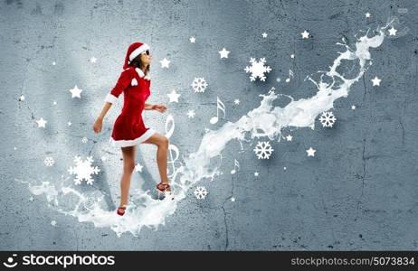 Santa girl. Attractive young woman in Santa suit walking on ladder