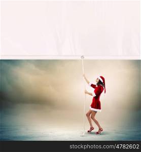 Santa girl. Girl in Santa costume pulling white blank banner. Place for text