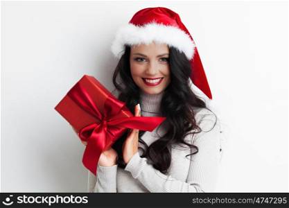 Santa girl holding christmas gift. Young happy woman in santa hat holding christmas gift box