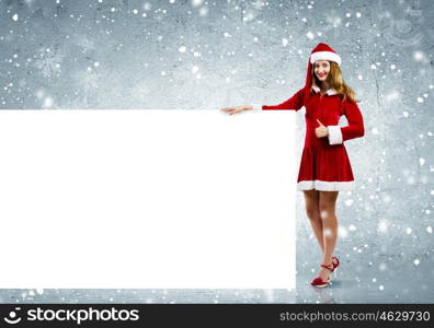 Santa girl with banner. Young attractive woman in santa suit holding blank banner. Place for text