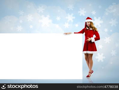 Santa girl with banner. Young attractive woman in santa suit holding blank banner. Place for text