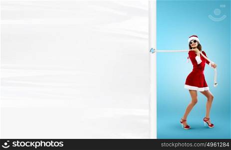 Santa girl with banner. Young pretty woman in Santa suit pulling blank white banner. Place for text