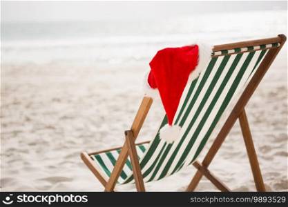 Santa hat kept on empty beach chair at tropical sand beach. Santa hat kept on empty beach chair