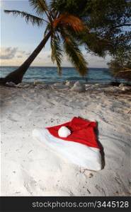 santa hat on sand under palm