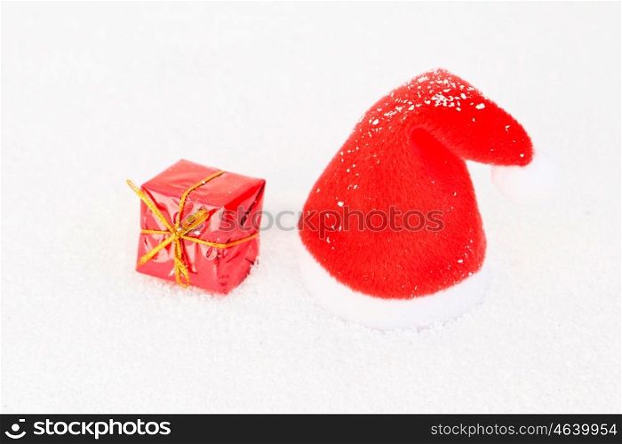 Santa hat on snow with one gift. Christmas in red