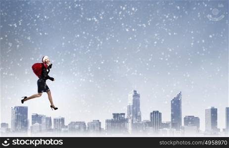 Santa is coming. Santa woman running with red gift bag on back