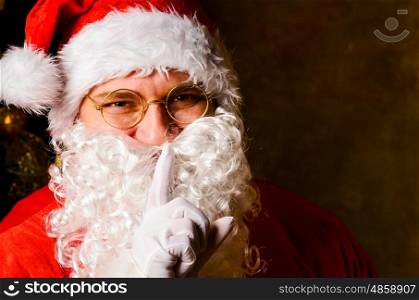 Santa keeps Christmas secrets. Santa Claus with finger on lips asking for silence