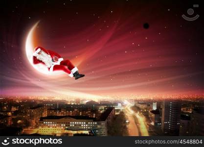 Santa on the moon. Santa Claus on the moon above a city at night