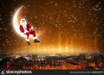 Santa on the moon. Santa Claus on the moon above a city at night