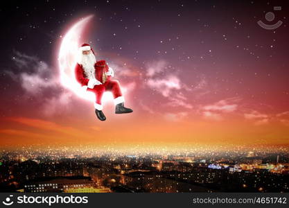 Santa on the moon. Santa Claus on the moon above a city at night