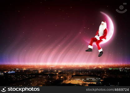 Santa on the moon. Santa Claus on the moon above a city at night