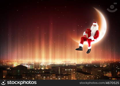 Santa on the moon. Santa Claus on the moon above a city at night