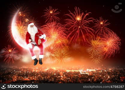 Santa on the moon. Santa Claus on the moon above a city at night