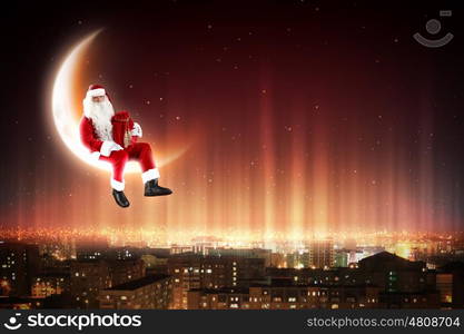 Santa on the moon. Santa Claus on the moon above a city at night