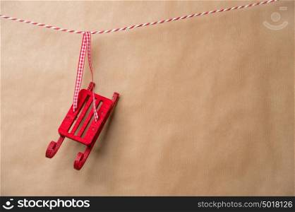 Santa's fairy Christmas decorative sleigh hanging on a ribbon. Old brown paper background. Lots of copyspace