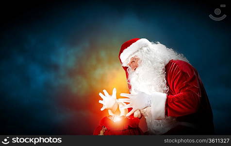 Santa with beard and red hat holding and looking into the sack