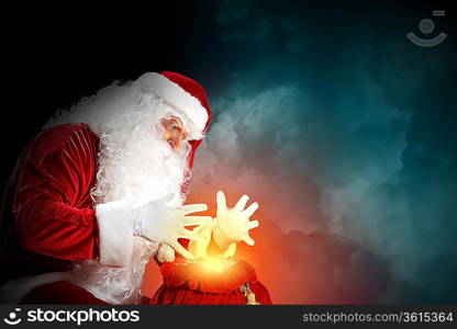 Santa with beard and red hat holding and looking into the sack