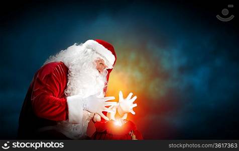 Santa with beard and red hat holding and looking into the sack