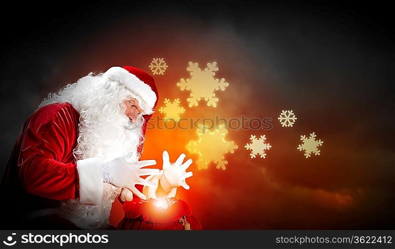 Santa with beard and red hat holding and looking into the sack