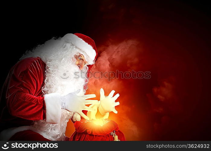 Santa with beard and red hat holding and looking into the sack