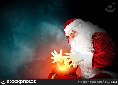 Santa with beard and red hat holding and looking into the sack