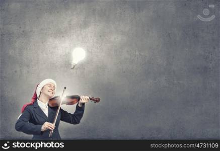 Santa woma play violin. Woman in formal suit and Santa hat playing violin