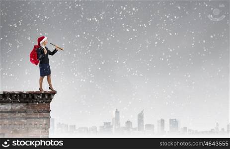Santa woman in search. Businesswoman in Santa hat on building top looking in spyglass