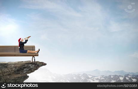 Santa woman in search. Businesswoman in Santa hat on rock top looking in spyglass