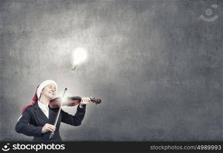 Santa woman play violin. Woman in formal suit and Santa hat playing violin