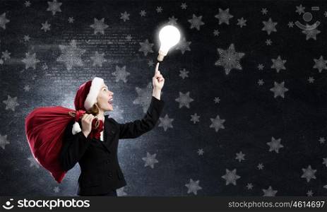 Santa woman. Santa woman with red bag on back pointing on light bulb with finger