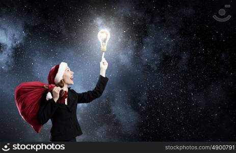 Santa woman. Santa woman with red bag on back pointing on light bulb with finger