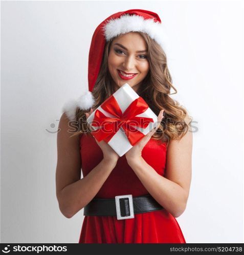 Santa woman with christmas gift. Smiling woman dressed in pin-up dress santa claus style holding christmas gift box