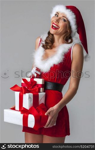 Santa woman with christmas gifts. Smiling woman dressed in pin-up dress santa claus style holding christmas gift boxes