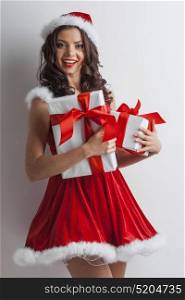 Santa woman with christmas gifts. Smiling woman dressed in pin-up dress santa claus style holding christmas gift boxes