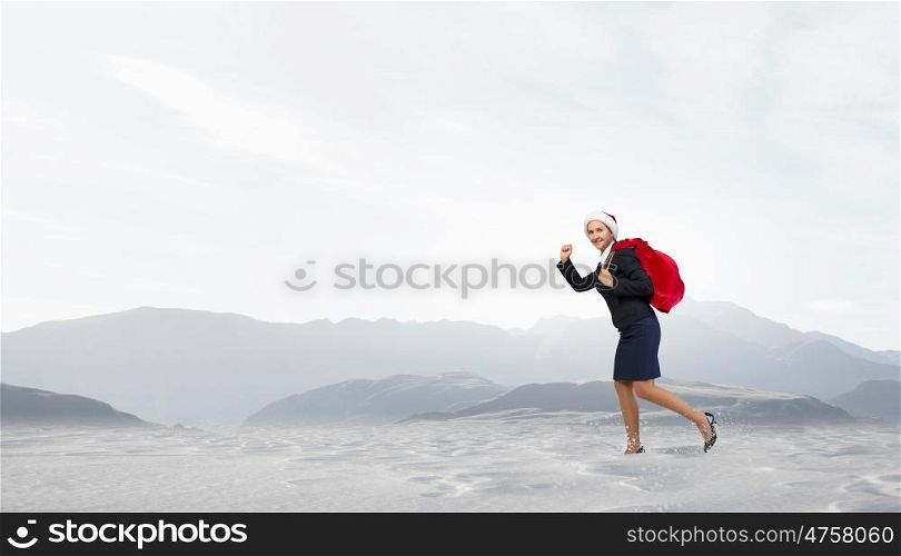 Santa woman with sack. Young businesswoman running big heavy Christmas sack on back
