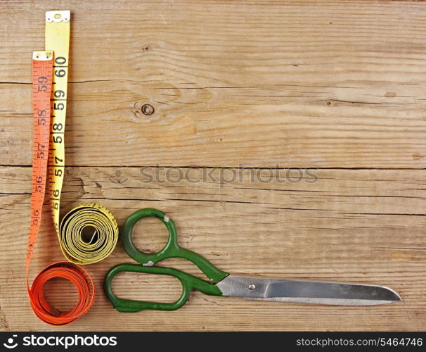 sartorial meter and scissors on the old wooden background