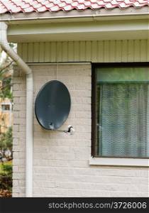 Satellite is attached to the brick wall of the house, vertical format