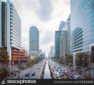 Sathorn intersection or junction with cars traffic, Bangkok Downtown skyline, Thailand. Financial district and business area. Smart urban city. Skyscraper and buildings at sunset.