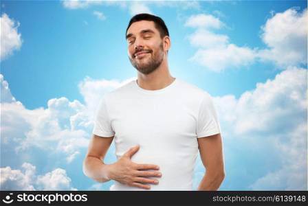 satisfaction, healthy eating and people concept - happy full man touching his tummy over blue sky and clouds background