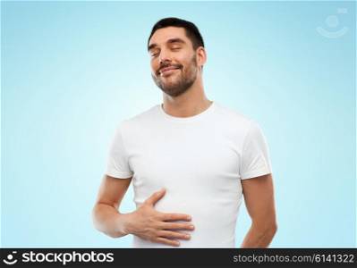 satisfaction, healthy eating and people concept - happy full man touching his tummy over blue background
