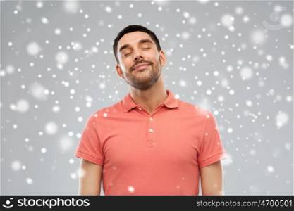 satisfaction, winter, christmas and people concept - happy man in polo t-shirt over snow on gray background