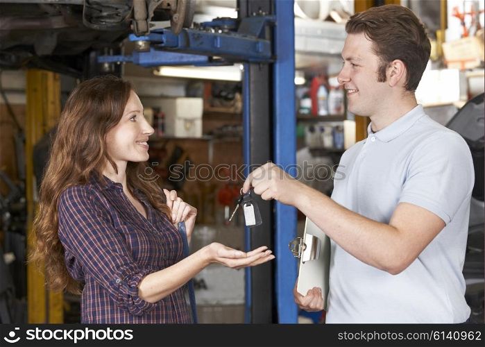 Satisfied Customer Collecting Car From Garage Mechanic